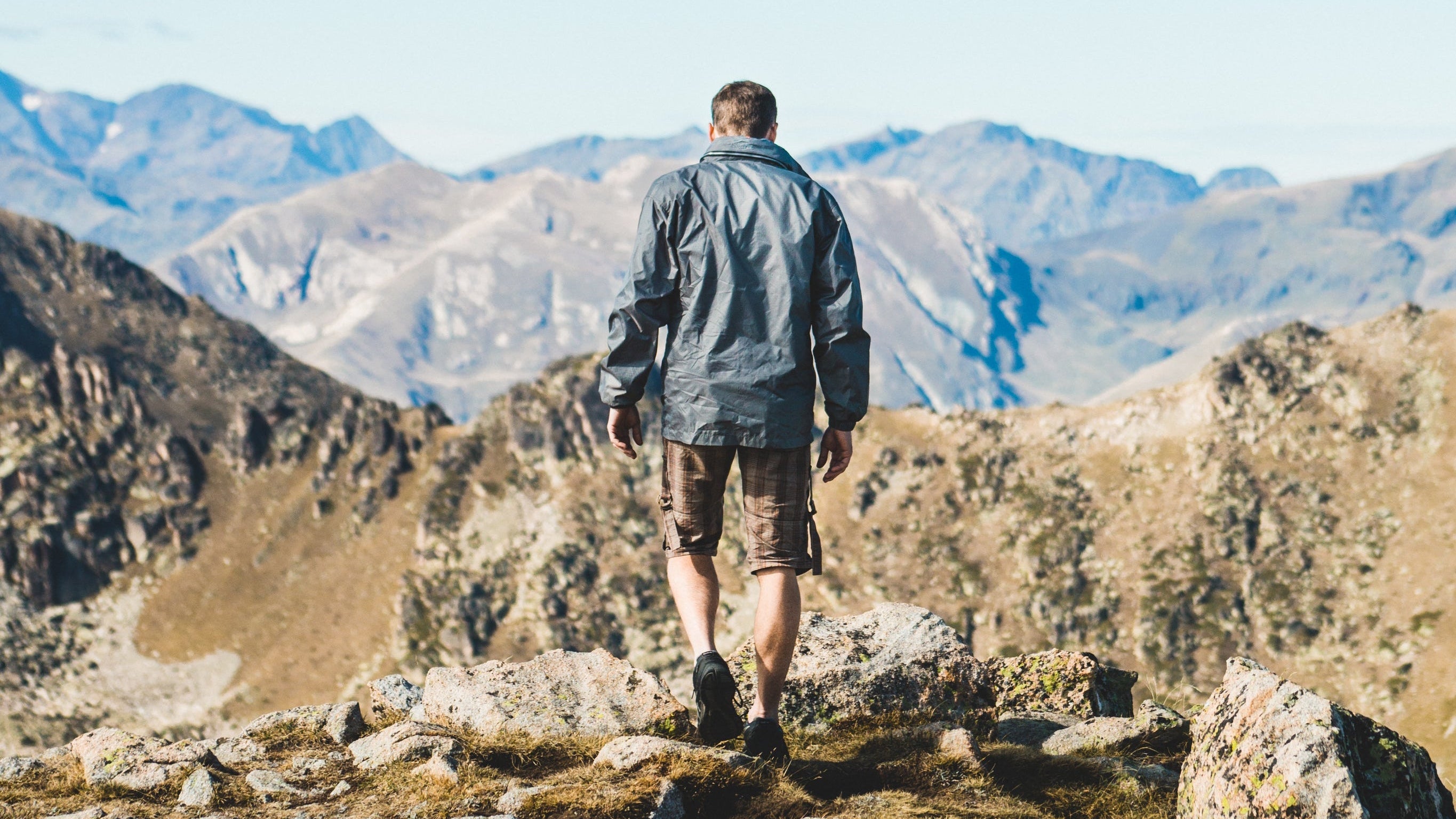 Person standing on a mountain trail with scenic mountains in the background